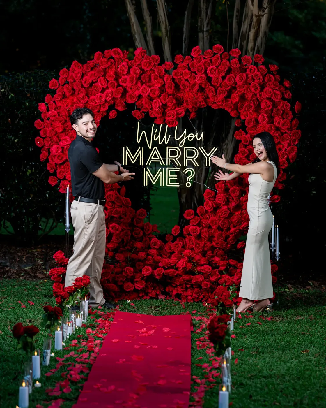 Pareja celebrando una propuesta de matrimonio bajo un arco de rosas